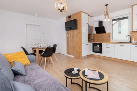 An open concept living and kitchen area with light wood finishes, a gray sofa, and dining furniture.