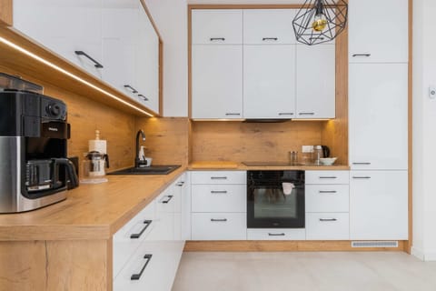 A contemporary kitchen with wooden cabinets, white drawers, and modern appliances such as an oven and stovetop.