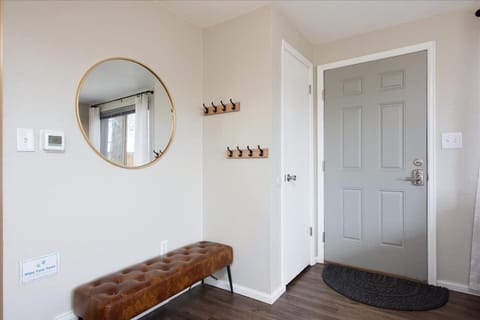 The stylish and inviting entryway with mid-mod bench, brass mirror and industrial hooks greet you upon arrival.