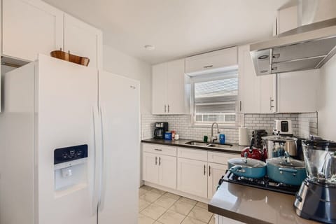 Enjoy the full kitchen with a refrigerator, oven, stove, microwave, coffee, creamers, mixers, spices, pots, pans, cooking supplies, cutlery, cups, plates, bowls, utensils, small appliances, view of the backyard, and many more essentials.