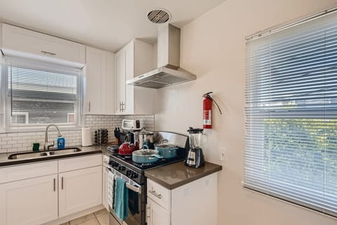 Enjoy the full kitchen with a refrigerator, oven, stove, microwave, coffee, creamers, mixers, spices, pots, pans, cooking supplies, cutlery, cups, plates, bowls, utensils, small appliances, view of the backyard, and many more essentials.
