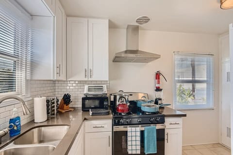 Enjoy the full kitchen with a refrigerator, oven, stove, microwave, coffee, creamers, mixers, spices, pots, pans, cooking supplies, cutlery, cups, plates, bowls, utensils, small appliances, view of the backyard, and many more essentials.