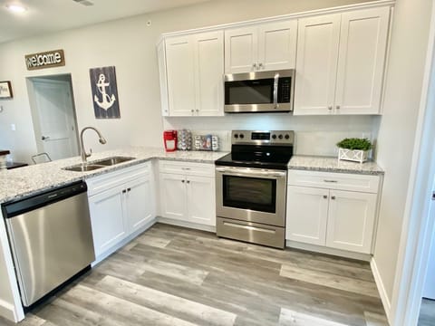 Open kitchen has full-sized stainless steel appliances and granite counters 