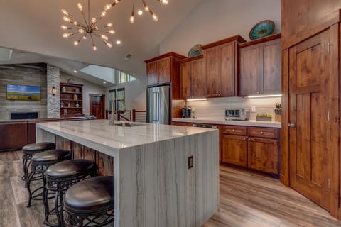 - Modern kitchen with marble waterfall island design
- Pendant lighting creates a stylish cooking space
- Stainless steel appliances with wood cabinetry