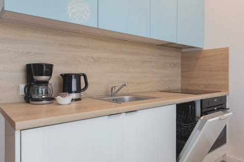 A small, modern kitchenette with blue cabinets and a wooden countertop. Essential appliances like a coffee maker and toaster are neatly arranged.