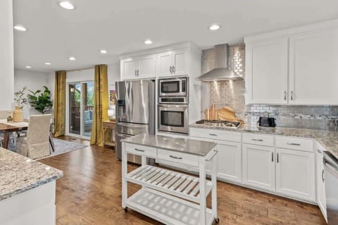 Chef’s kitchen with granite countertops, gas stove & island flows into dining area.