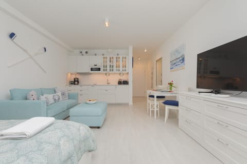 Studio space decorated with marine accents and equipped with a double bed, sofa bed, TV and kitchenette.