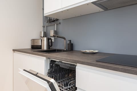 A modern kitchen with a long countertop, sleek appliances, and a view of the living area.