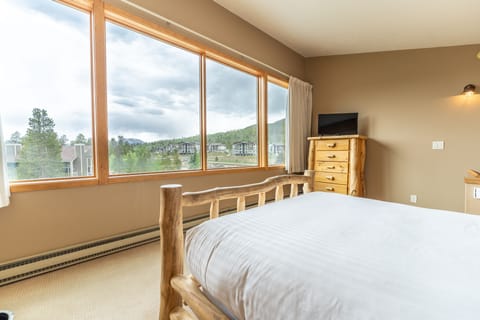 Upstairs bedroom featuring a queen bed, private bathroom, and scenic views from the windows.