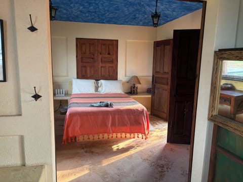 Queen bed. Shutters can be opened for natural light and cooling breezes.