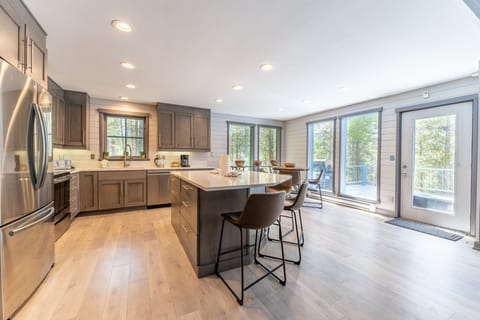 The full-sized kitchen featuring stainless steel appliances, hardwood flooring, a kitchen island, and breakfast bar seating.