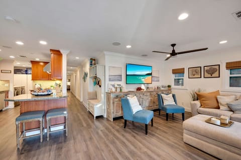 Bright and spacious living room with comfortable seating, shows the hallway to the bedroom