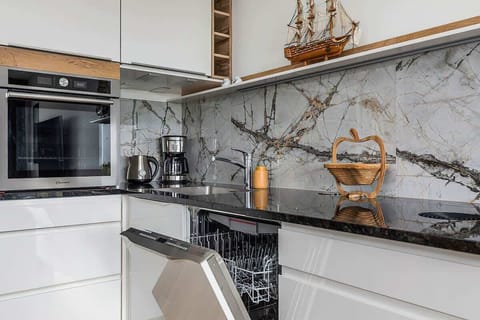 A modern kitchenette with wooden cabinets and a marble countertop, equipped with a coffee maker and kettle.
