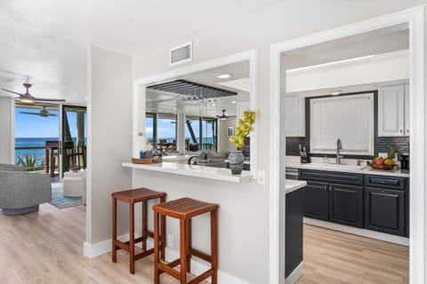 Kitchen pass-through bar with two stools and peek-a-boo ocean views beyond.