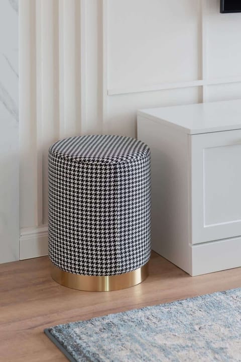 A small, stylish pouf in a neutral tone, adding functionality and comfort to the living space.