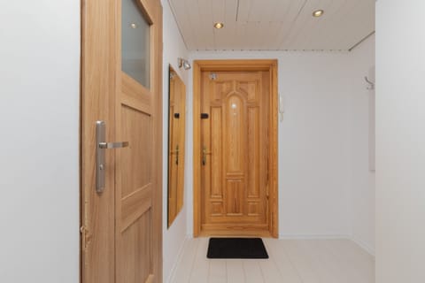 The entryway features a wooden door, practical storage, and neutral decor. The design is clean and functional.
