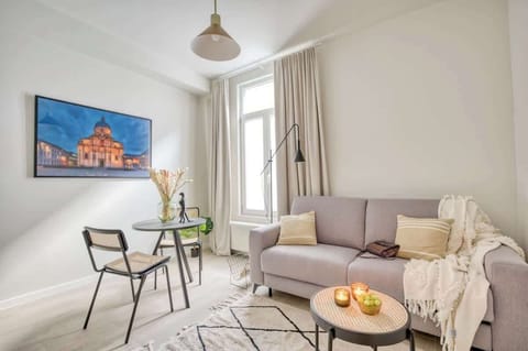 The lovely living room area complete with a small dining set, sofa couch, cozy area rug, coffee table, and a lamp making for an ideal reading set up.