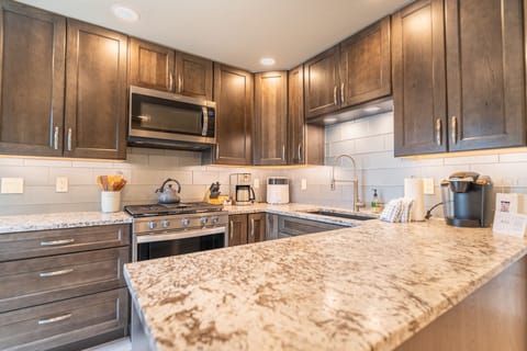 Full size kitchen with stainless steel appliances, granite countertops and hardwood flooring.