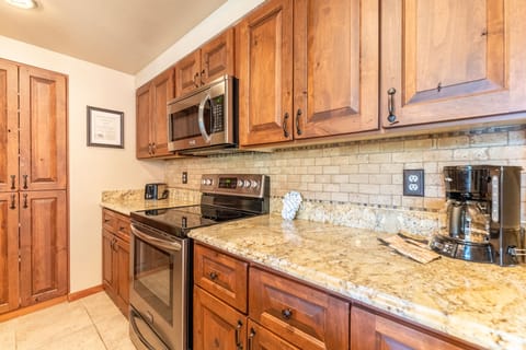 Full size kitchen with stainless steel appliances and granite countertops.
