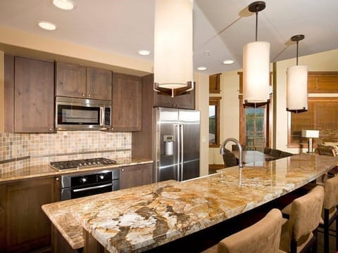 The fully-equipped kitchen features granite countertops, stainless steel appliances and a breakfast bar