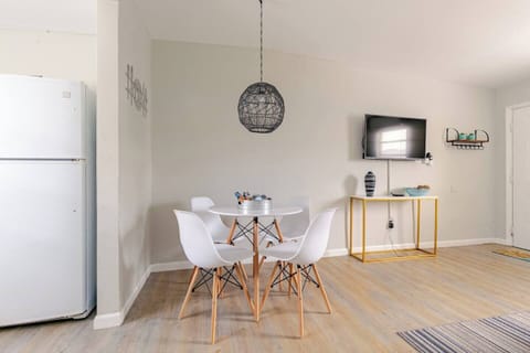 Bright dining area featuring a round table and stylish white chairs.