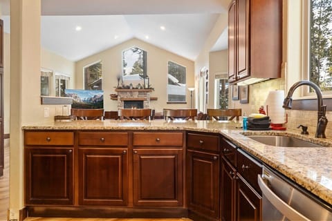 The kitchen boasts ample seating space with a bar featuring four barstools, a large island with two stools, and a dining nook with a table and chairs for six.