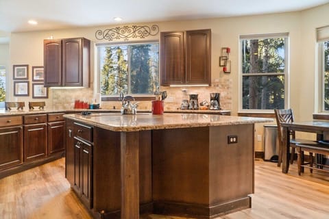 The fully equipped kitchen is a beautiful space with granite countertops, stainless steel appliances, and an over-the-sink window with tree views.