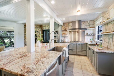 Looking down the length of the kitchen.  Dishwasher, Range, and Farm sink visible.