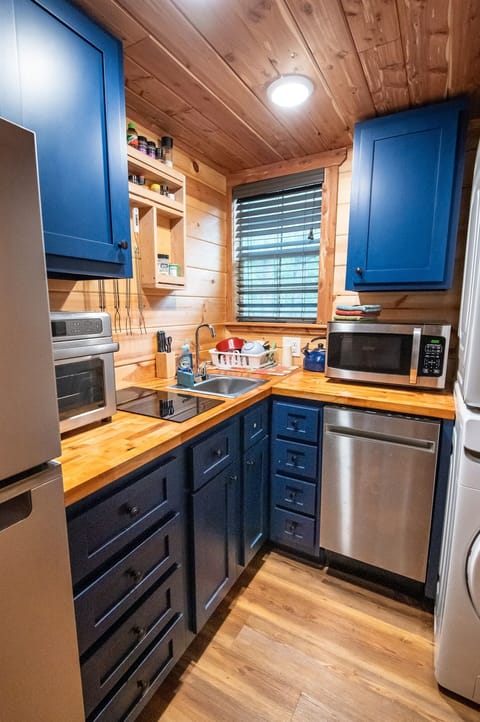 - Bright kitchen with blue cabinets and wood counters - Organized space with spices and cookware ready - Perfect for cooking during your forest cabin getaway forest retreat
