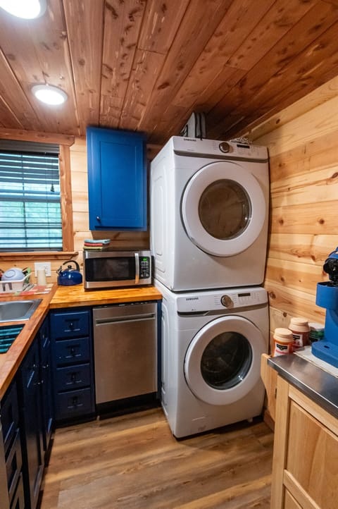 - Compact kitchen corner with washer dryer setup - Blue cabinets and wood counters add cozy cabin charm - Full convenience for extended forest stays forest cabin retreat
