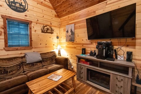 - Warm wood-paneled living room with comfy seating - Large TV and fireplace add inviting cabin vibes - Perfect for relaxing after forest adventures