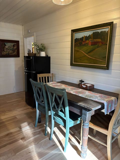 Charming dining area with a rustic wooden table, colorful chairs, and artwork on the wall.