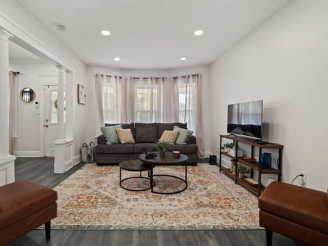Spacious living area with comfy seating and TV view - Decorative rug and soft lighting make it inviting - Perfect for family movie nights or group hangouts