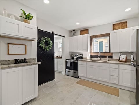 Fully equipped kitchen with stainless steel appliances - White cabinetry and modern finishes with barn door style - Bright space ready for home-cooked meals