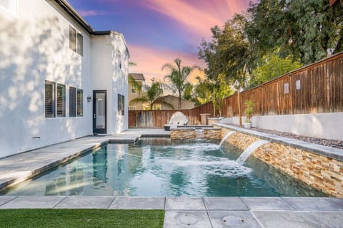 Relax in our backyard with a heated pool and spa. Enjoy the sun, palm trees, and a cozy patio with vibrant flowers.