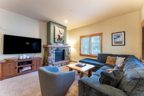 Cozy up in your spacious living room featuring plush seating, stone fireplace, and entertainment center for memorable mountain evenings.