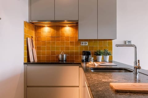 Warm kitchen area featuring golden backsplash and modern appliances.