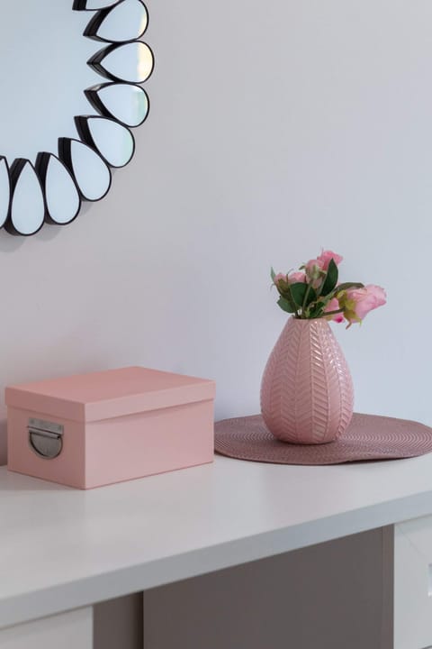 A decorative setup featuring a pink vase and box on a minimalist shelf, adding charm to the interior.