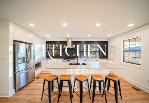 This stunning kitchen features a massive island, black tile backsplash, and chef-ready appliances — ideal for hosting in style.