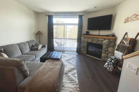 Open living area with natural light, mounted TV & gas fireplace. Walk-out patio.