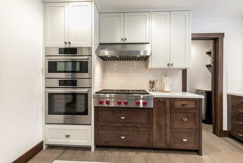 The fully equipped kitchen features top-of-the-line stainless steel appliances such as the 36” Wolf stovetop range, ample counter space, and a walk-in pantry.