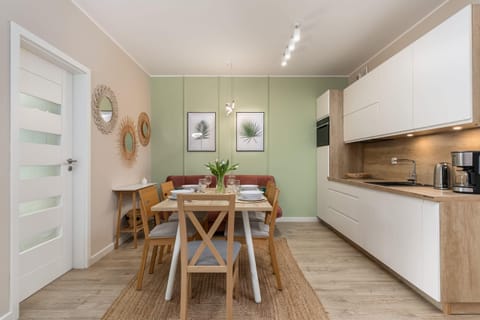A kitchen with clean white cabinets, wooden accents, and a fully equipped dining area.
