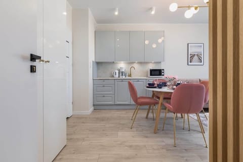  A hallway leading to a dining and living area, with soft lighting and wooden floors.