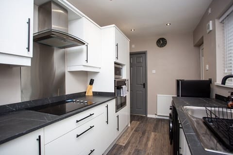 Kitchen well equipped with washing machine, cooker, fridge, microwave, kettle and coffee machine.