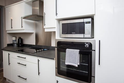 Kitchen well equipped with washing machine, cooker, fridge, microwave, kettle and coffee machine.