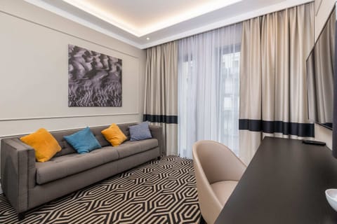 A stylish living area featuring a gray sofa, bright yellow cushions, and elegant curtains.