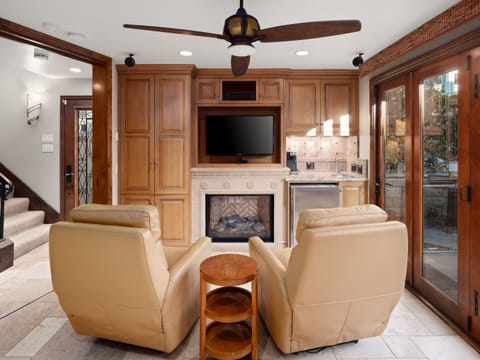 Cozy sitting area with two plush leather recliners for relaxation. Expansive glass doors open to a charming outdoor patio with seating.