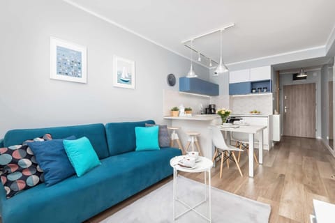 A modern living room decorated in shades of blue and white, featuring a cozy blue sofa with matching pillows, a minimalist coffee table, and bright natural lighting from large windows.