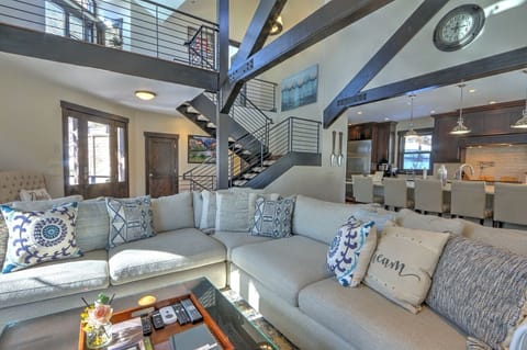 Living area with plush seating, uniquely crafted beams, & statement staircase
