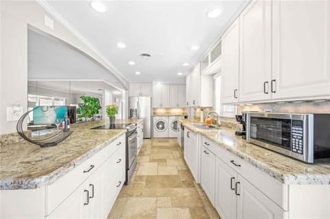 Open layout kitchen with island. Full set of appliances, including a Keurig coffee maker and basic kitchen utensils.